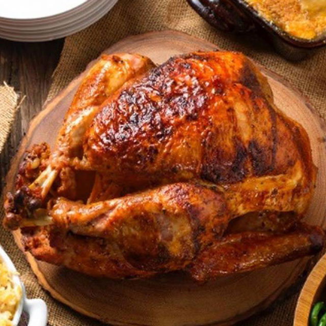 A Roasted Turkey is Pictured with sides, desserts and trimmings